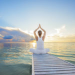 Caucasian woman practicing yoga at seashore